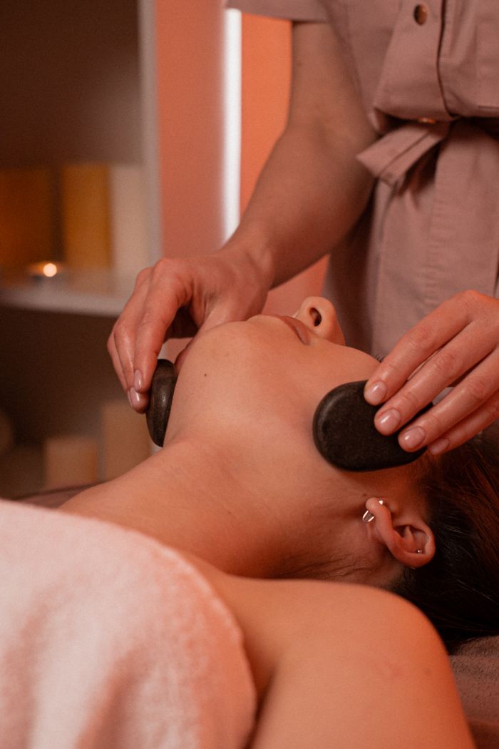 Home Relaxing stone massage on woman's face in a calm spa environment.