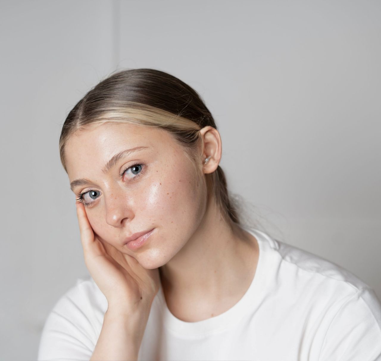 Home Close-up portrait of a young woman with clear skin and a thoughtful expression indoors.