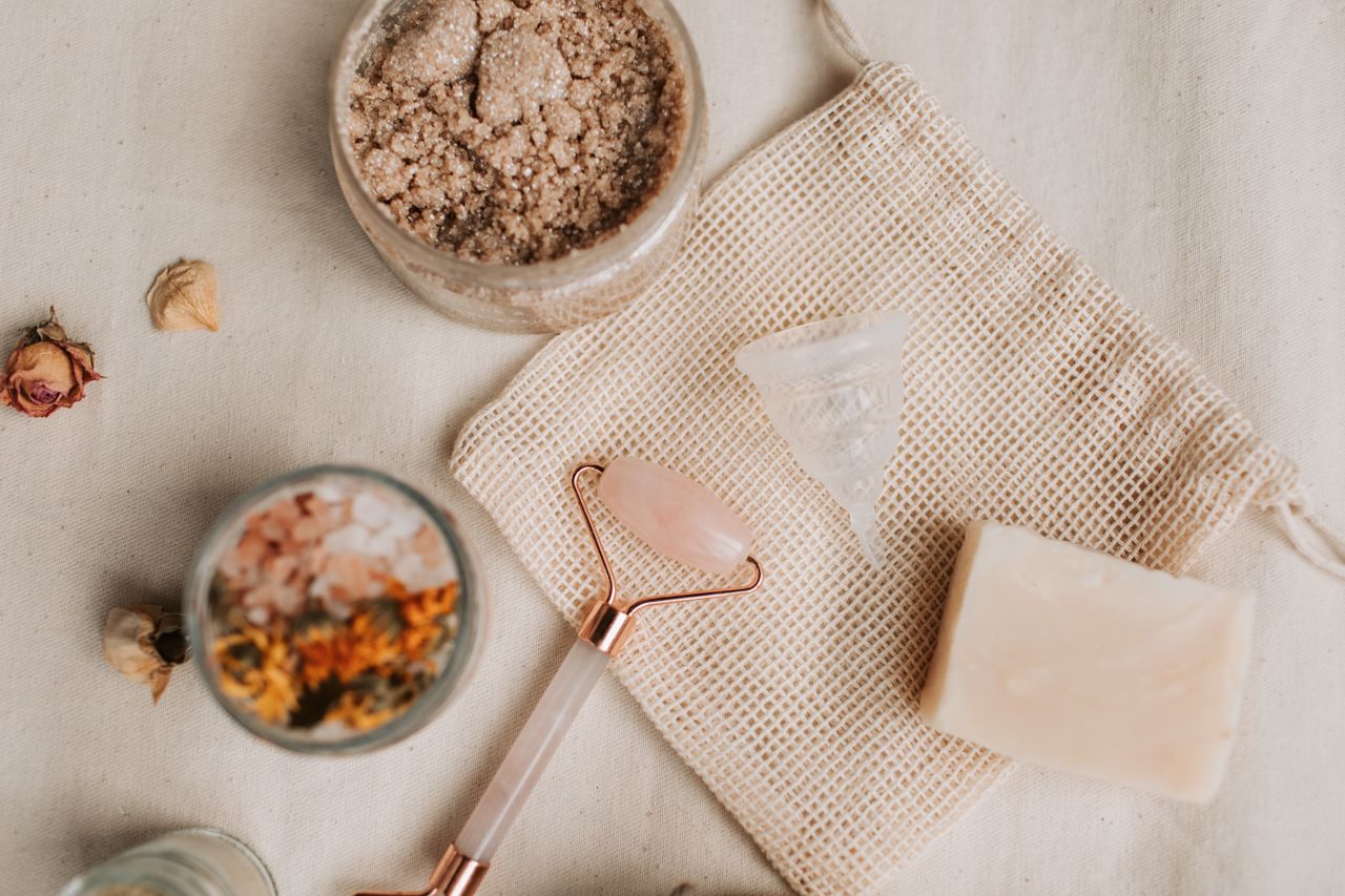 Home Aesthetic flat lay of natural skincare products including a jade roller and sugar scrub.