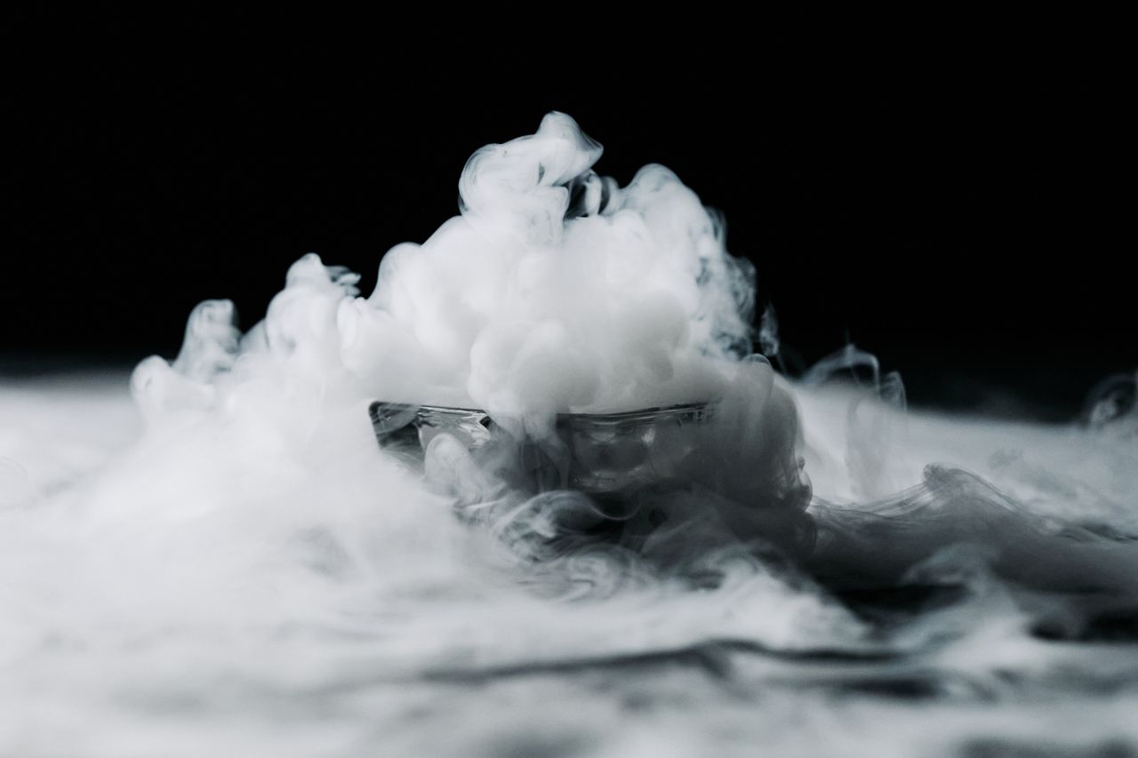 A captivating visual of smoke swirling in a glass bowl against a dark background, creating a mystical effect.